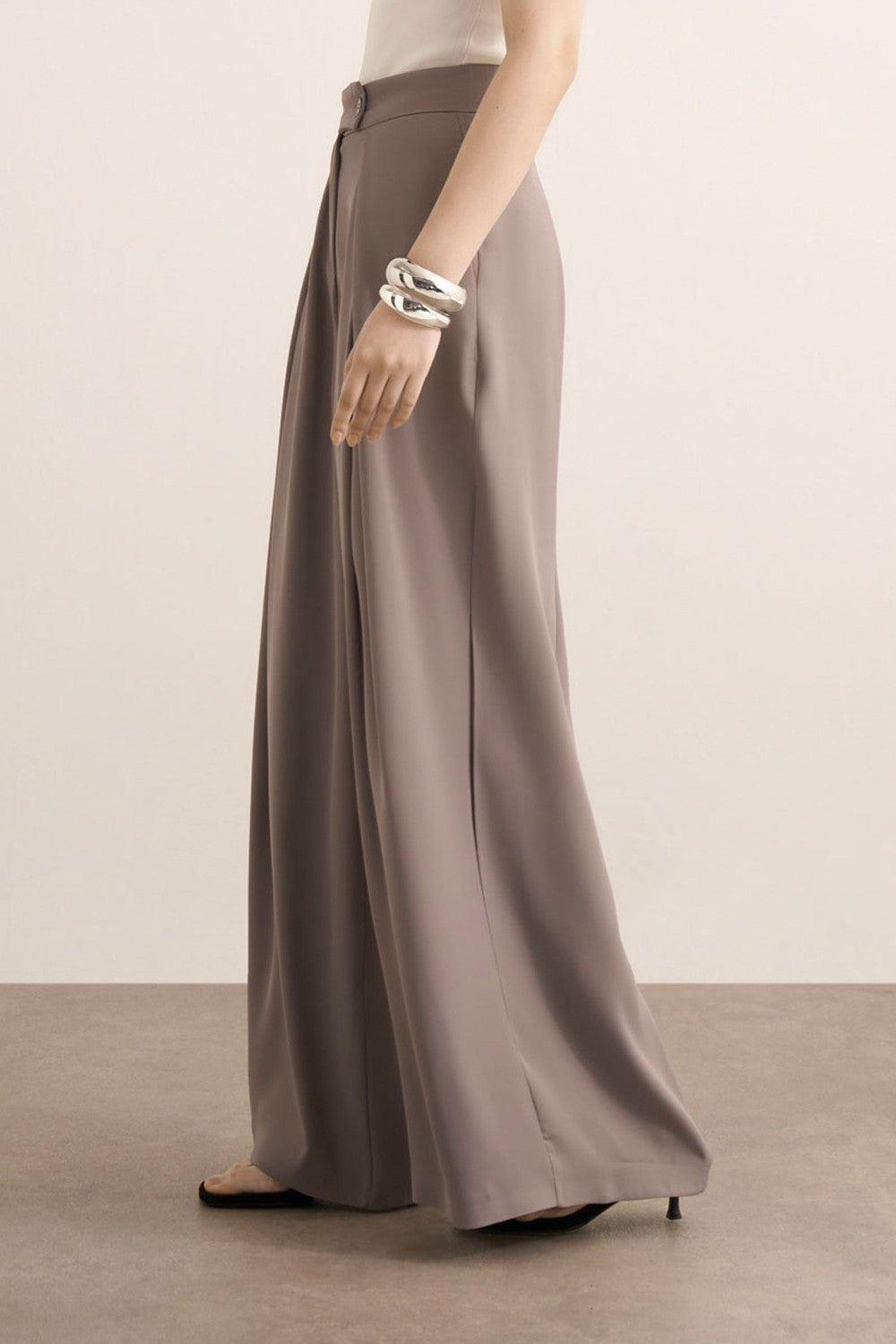 Cherianne.com Leona high-waisted wide-leg trousers in taupe with pleated details and side pockets on a model.