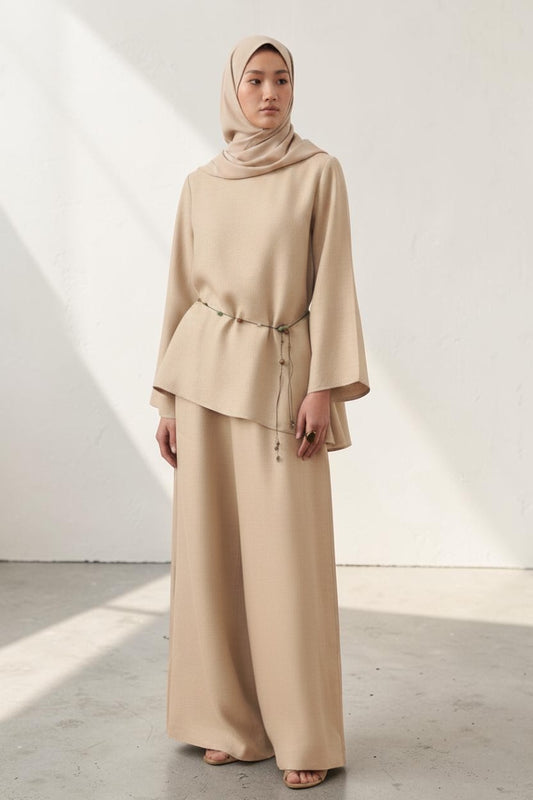 Cherianne.com beige linen blouse with wide sleeves, asymmetric hem, and waist tie, worn with matching wide-leg trousers.
